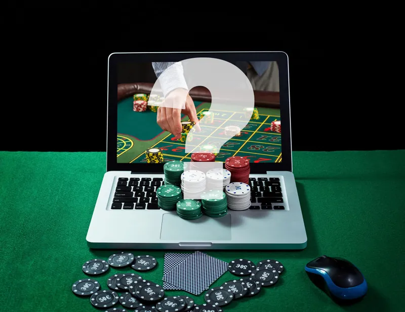 Notebook com mesa de roleta na tela, fichas e cartas sobre feltro verde, representando casas de apostas online