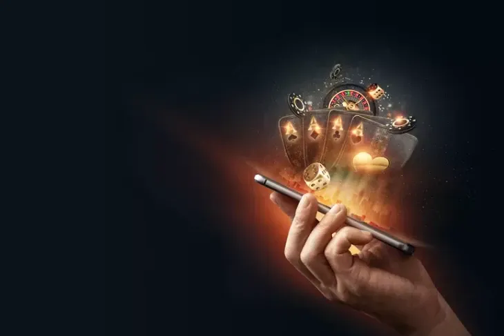 Mão segurando celular de onde saem cartas, roleta, dados e fichas, capa sobre depósitos e saques na PagBets